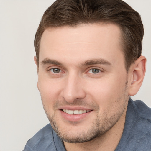 Joyful white young-adult male with short  brown hair and grey eyes