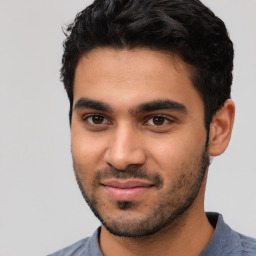 Joyful latino young-adult male with short  black hair and brown eyes