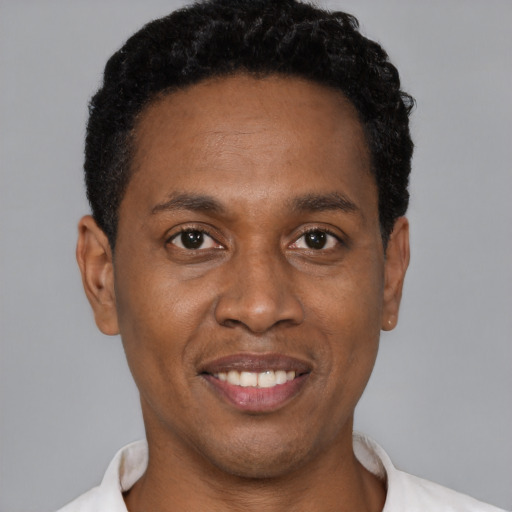 Joyful black young-adult male with short  black hair and brown eyes