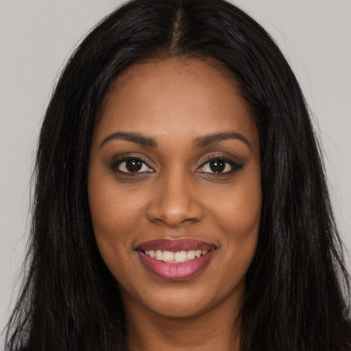 Joyful black young-adult female with long  black hair and brown eyes