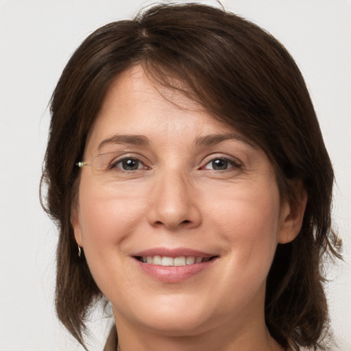 Joyful white young-adult female with medium  brown hair and grey eyes