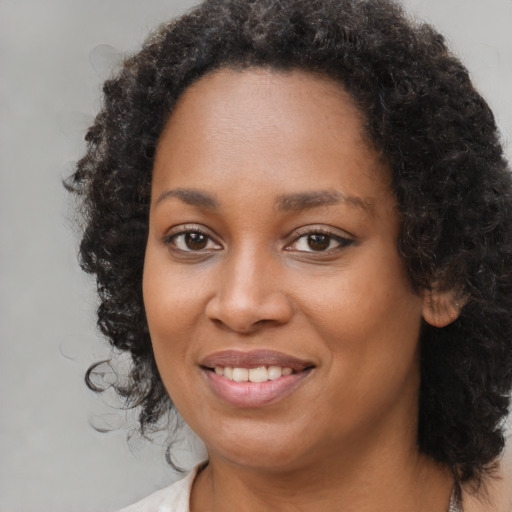 Joyful black young-adult female with long  brown hair and brown eyes