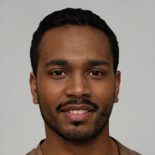 Joyful black young-adult male with short  black hair and brown eyes