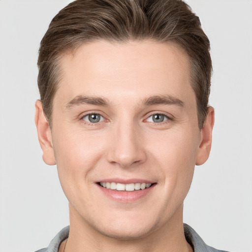 Joyful white young-adult male with short  brown hair and grey eyes