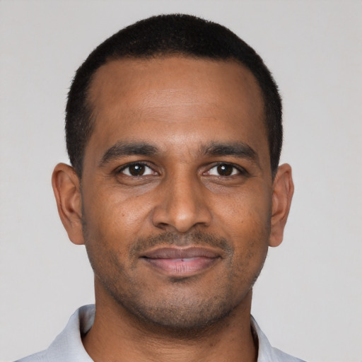 Joyful black young-adult male with short  black hair and brown eyes