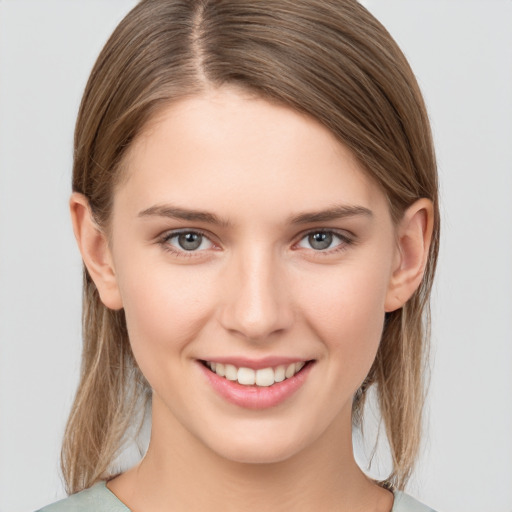 Joyful white young-adult female with medium  brown hair and grey eyes