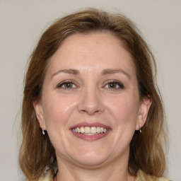 Joyful white adult female with medium  brown hair and blue eyes