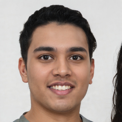 Joyful latino young-adult male with short  black hair and brown eyes