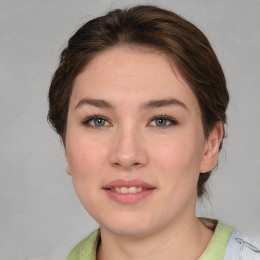 Joyful white young-adult female with medium  brown hair and grey eyes