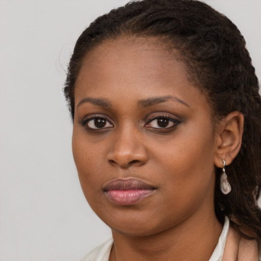 Joyful black young-adult female with long  brown hair and brown eyes