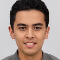 Joyful latino young-adult male with short  brown hair and brown eyes