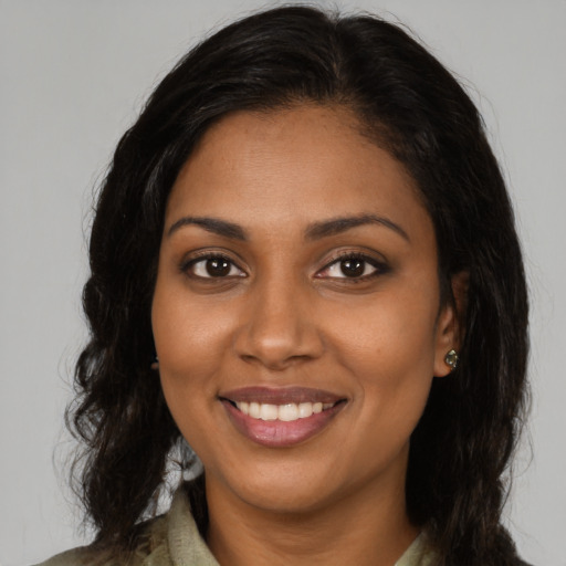 Joyful black young-adult female with long  brown hair and brown eyes