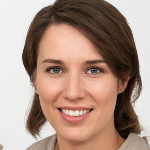 Joyful white young-adult female with medium  brown hair and grey eyes