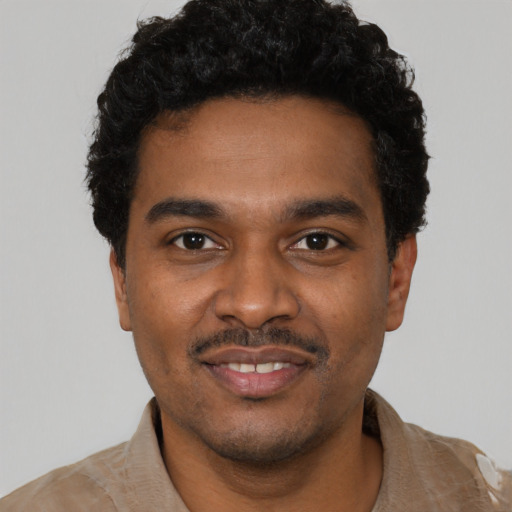 Joyful black young-adult male with short  black hair and brown eyes