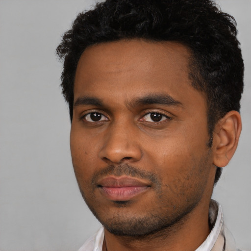 Joyful black young-adult male with short  black hair and brown eyes