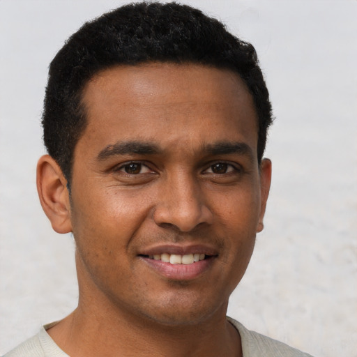 Joyful black young-adult male with short  brown hair and brown eyes