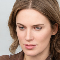 Joyful white young-adult female with long  brown hair and blue eyes