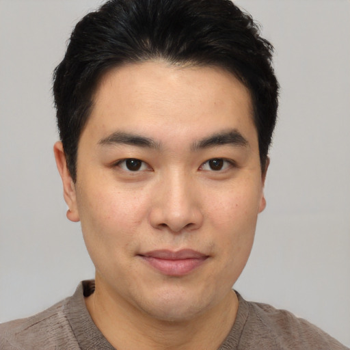 Joyful asian young-adult male with short  brown hair and brown eyes