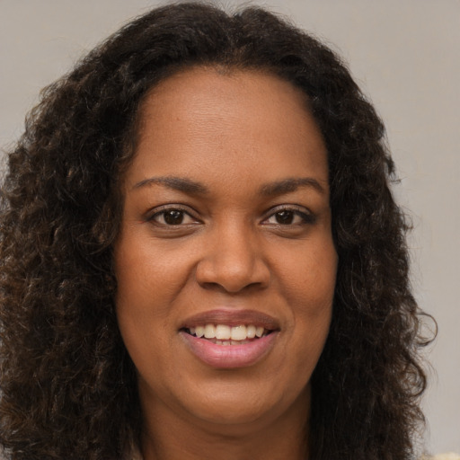 Joyful black young-adult female with long  brown hair and brown eyes