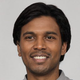 Joyful latino young-adult male with short  black hair and brown eyes