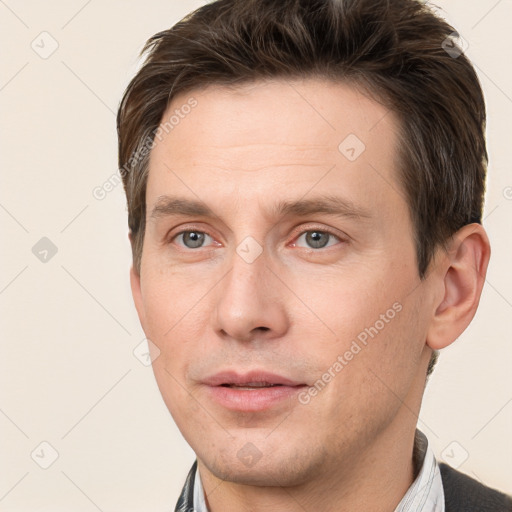 Joyful white young-adult male with short  brown hair and grey eyes