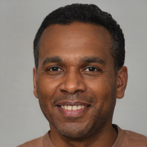 Joyful black young-adult male with short  black hair and brown eyes