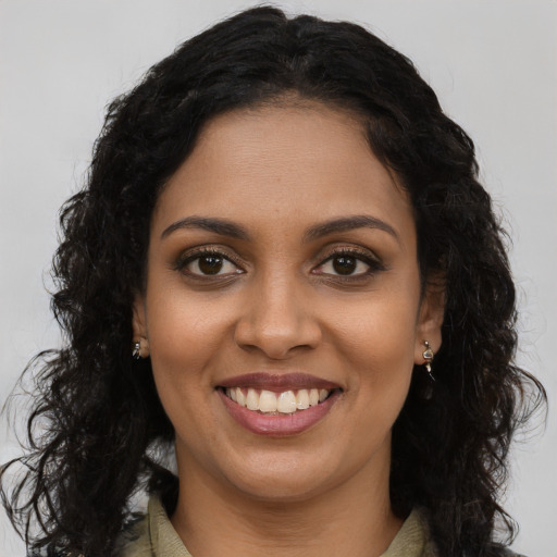 Joyful black young-adult female with long  brown hair and brown eyes