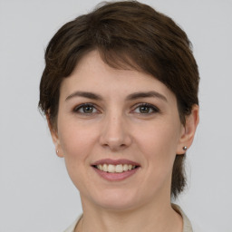 Joyful white young-adult female with medium  brown hair and grey eyes