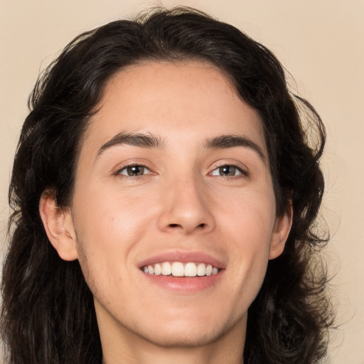 Joyful white young-adult male with long  brown hair and brown eyes