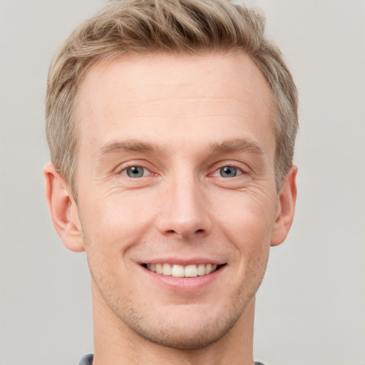 Joyful white young-adult male with short  brown hair and grey eyes