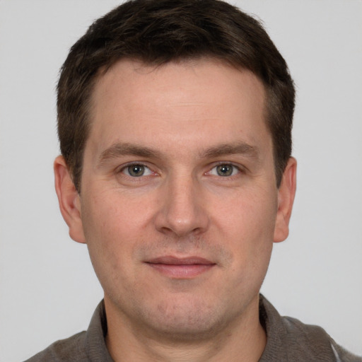 Joyful white young-adult male with short  brown hair and grey eyes