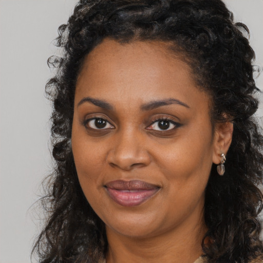 Joyful black young-adult female with long  brown hair and brown eyes