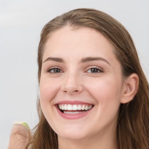 Joyful white young-adult female with long  brown hair and blue eyes