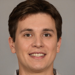 Joyful white young-adult male with short  brown hair and grey eyes