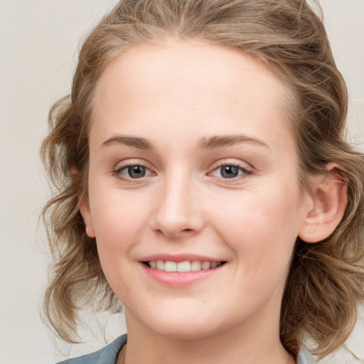 Joyful white young-adult female with medium  brown hair and blue eyes