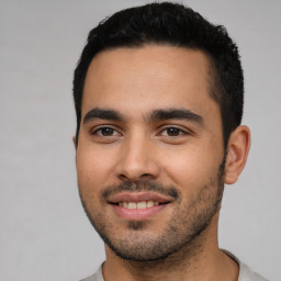 Joyful latino young-adult male with short  black hair and brown eyes