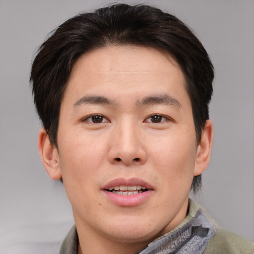Joyful asian young-adult male with short  brown hair and brown eyes
