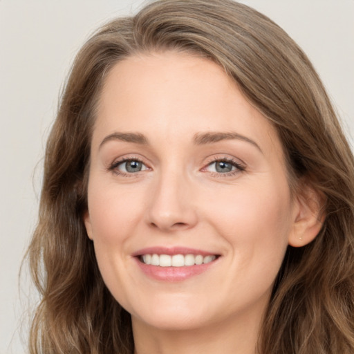 Joyful white young-adult female with long  brown hair and blue eyes