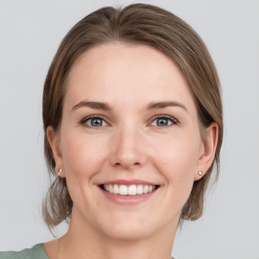 Joyful white young-adult female with medium  brown hair and grey eyes