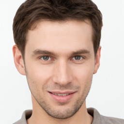 Joyful white young-adult male with short  brown hair and grey eyes