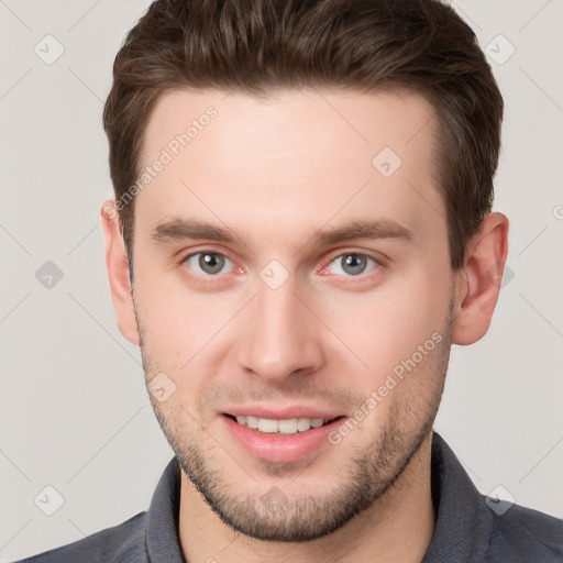 Joyful white young-adult male with short  brown hair and grey eyes