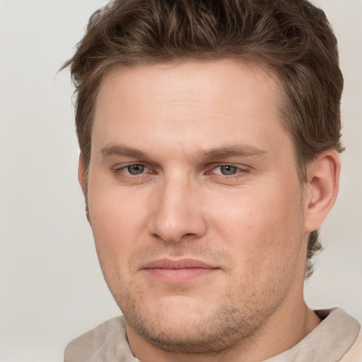 Joyful white young-adult male with short  brown hair and grey eyes