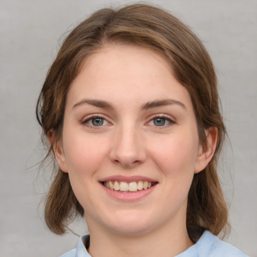 Joyful white young-adult female with medium  brown hair and green eyes