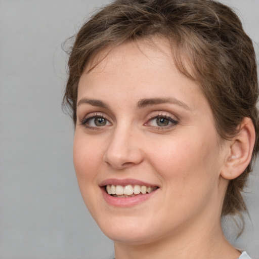 Joyful white young-adult female with medium  brown hair and grey eyes