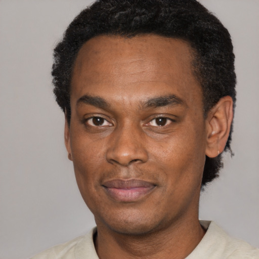 Joyful black adult male with short  black hair and brown eyes