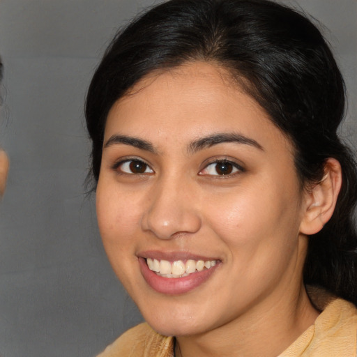 Joyful latino young-adult female with long  brown hair and brown eyes