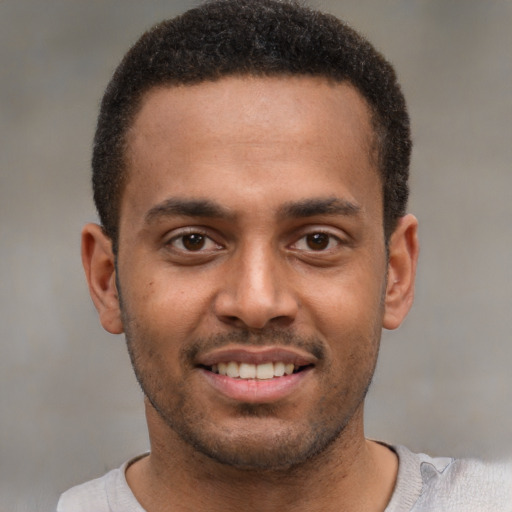 Joyful black young-adult male with short  brown hair and brown eyes