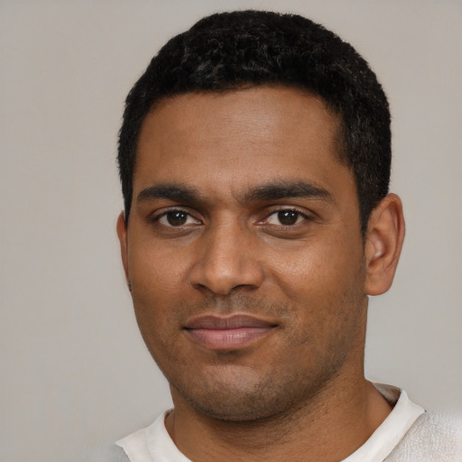 Joyful black young-adult male with short  black hair and brown eyes