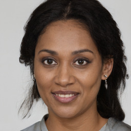 Joyful black adult female with long  brown hair and brown eyes