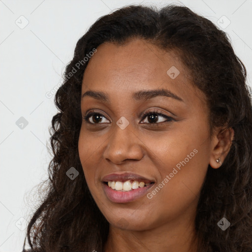 Joyful black young-adult female with long  brown hair and brown eyes